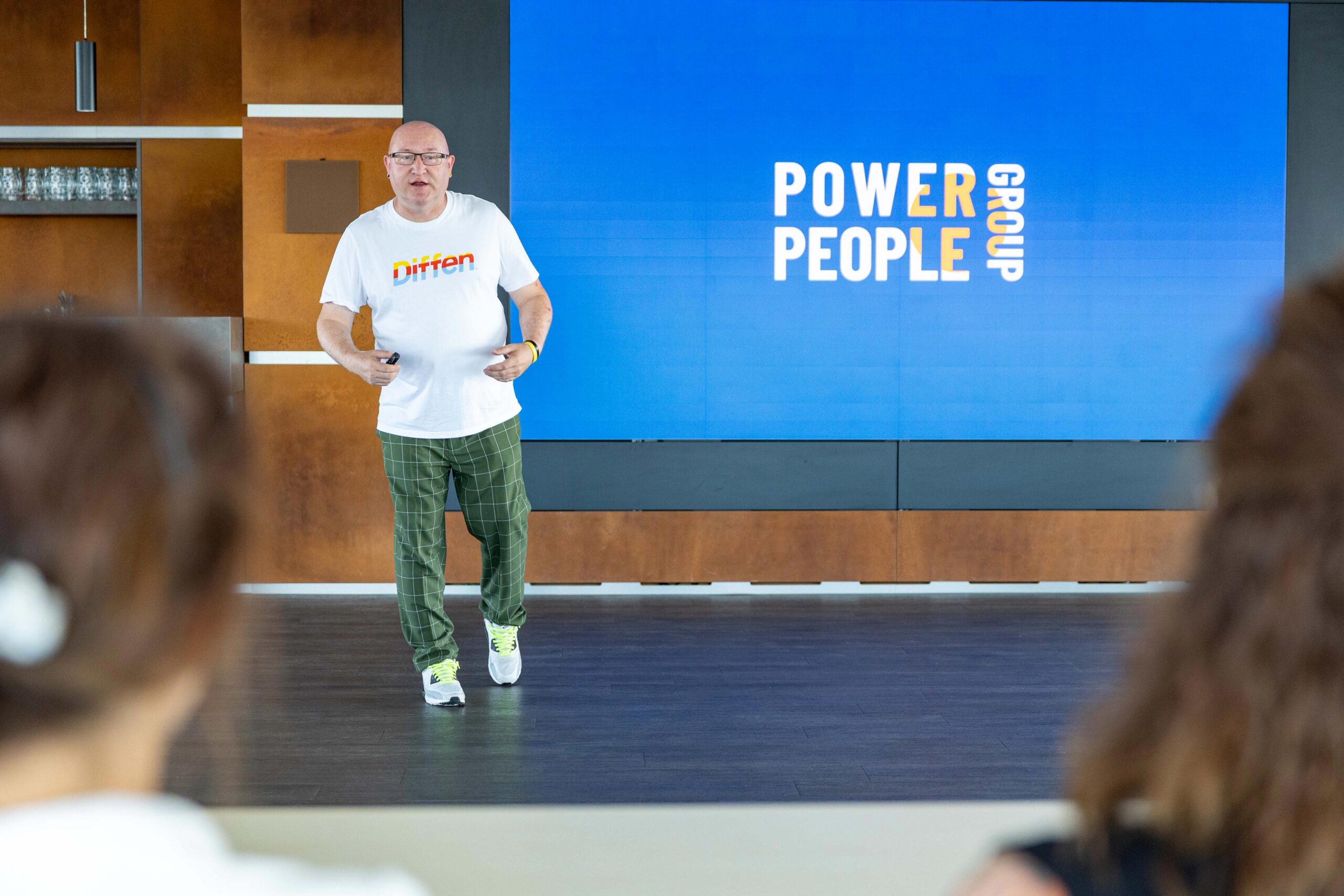 Vortrag zur Power People Group: Redner vor einer Leinwand mit dem Logo der Gruppe